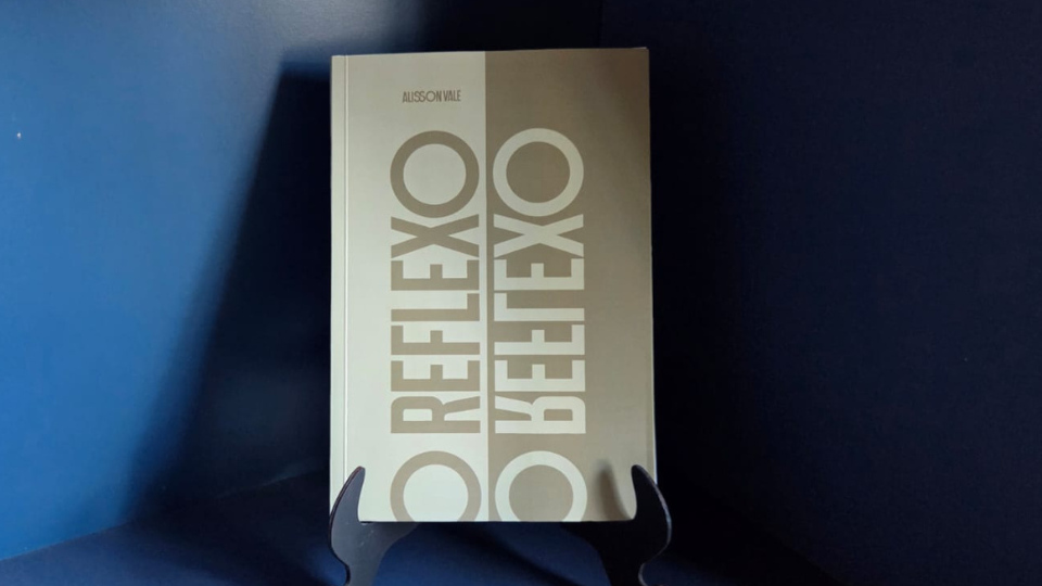 Banner tipográfico do livro O Reflexo em tons dourados.
